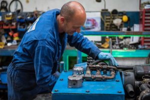 Person in blue overalls repairing a winch