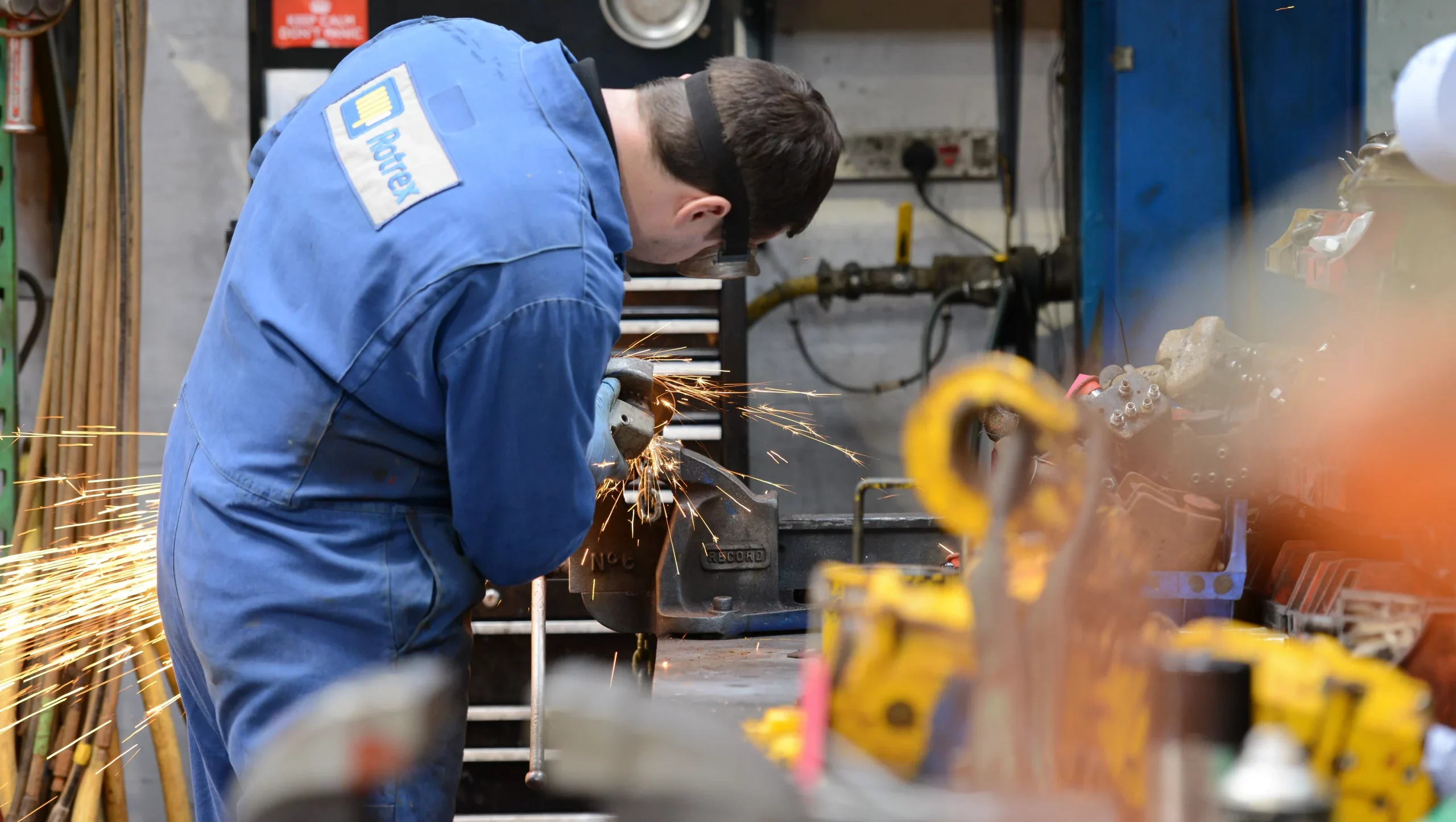 Rotrex Employee in blue overalls performing maintenance on some parts